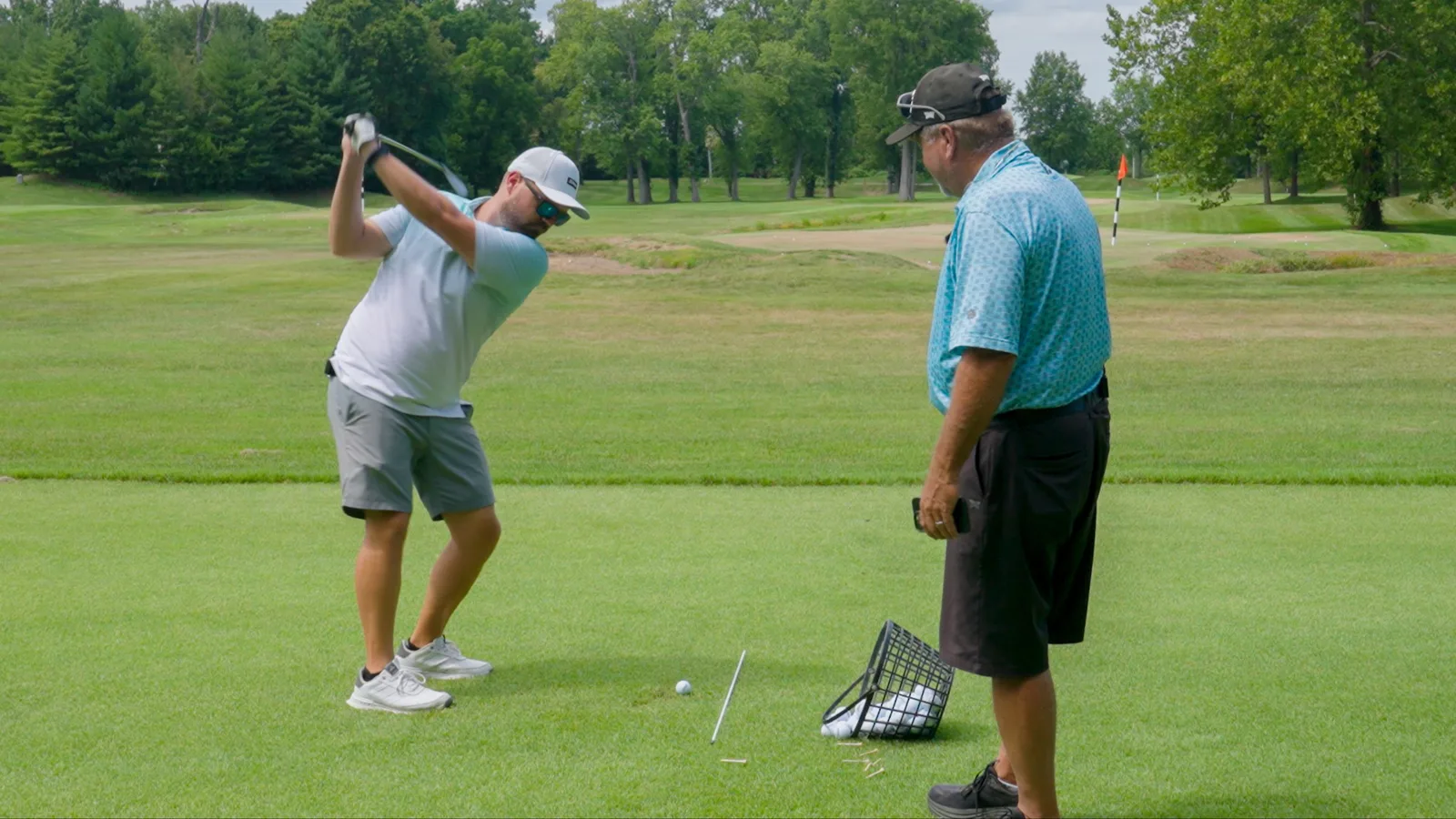 Coach Ed Schwent watching a golfer's swing on the range